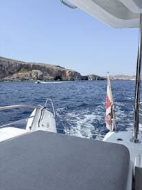 A scenic view from the deck of a boat cruising past stunning coastal cliffs, showcasing the beauty of the open sea.