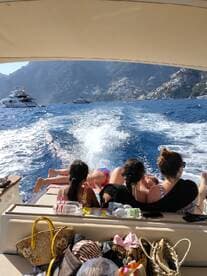 A group of friends and family relax on the back of a boat, enjoying the stunning coastal scenery — a perfect day on the water.