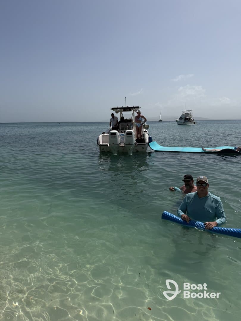 A group enjoys a sunny day in clear waters, with a boat anchored nearby — perfect for a fun-filled day on the water.
