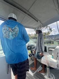 Two individuals are seen inside the helm area of a boat, showcasing the cabin's layout and features — perfect for fishing trips or leisurely cruises.