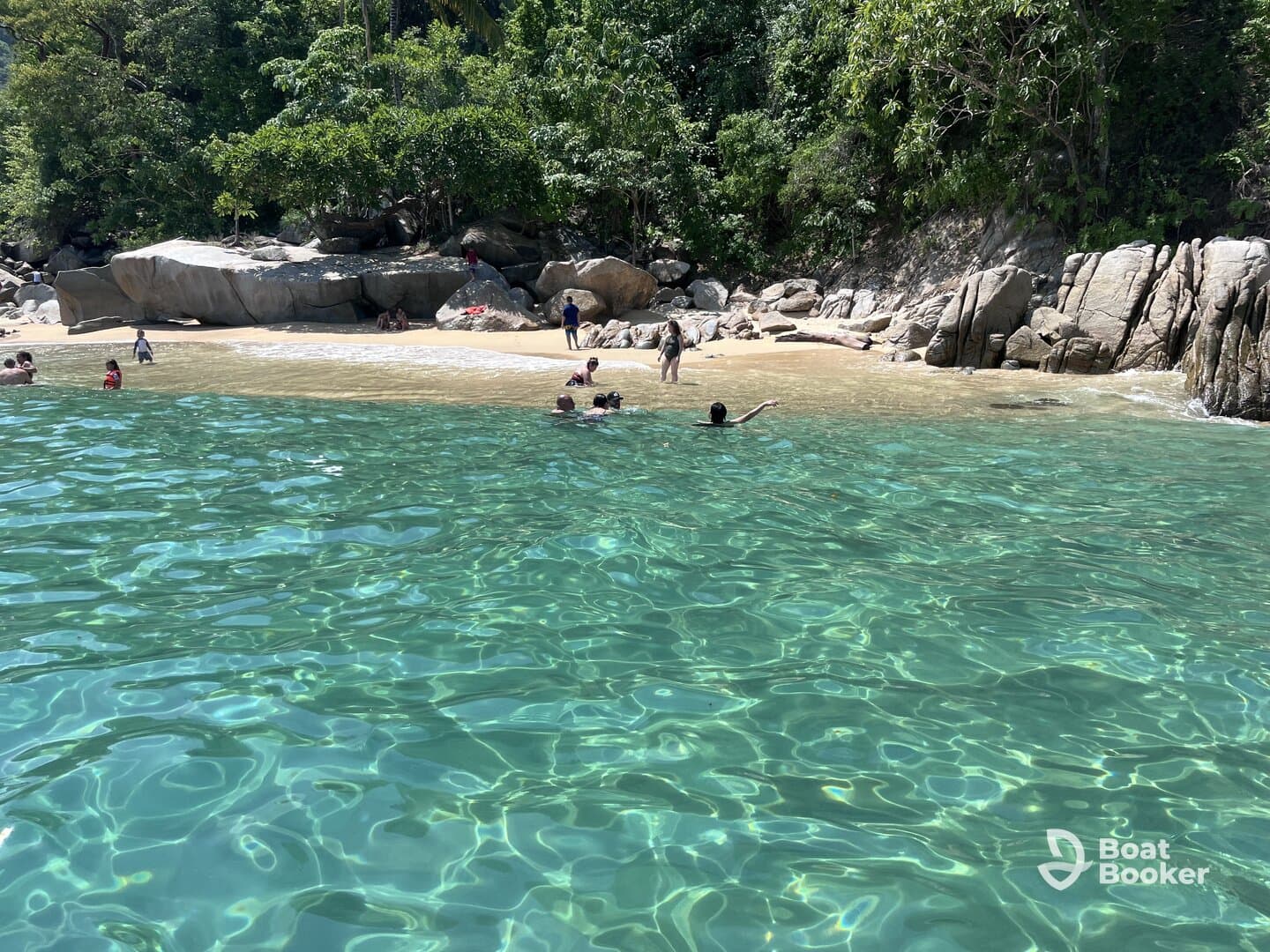 A lively beach scene with people enjoying the clear waters and sandy shore, perfect for a fun day of swimming and relaxation.