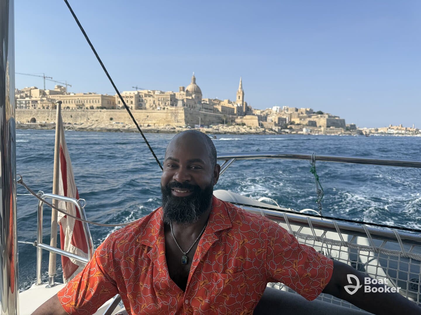 A smiling man enjoys a scenic boat ride with a stunning cityscape in the background, perfect for capturing memorable vacation moments.