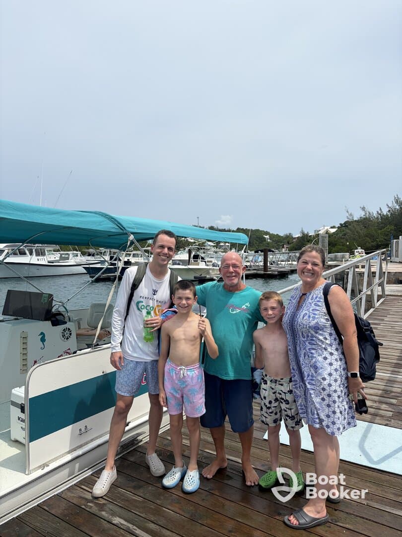 A cheerful family poses together at the dock next to their boat, capturing a memorable moment before their adventure on the water.