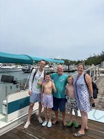 A cheerful family poses together at the dock next to their boat, capturing a memorable moment before their adventure on the water.