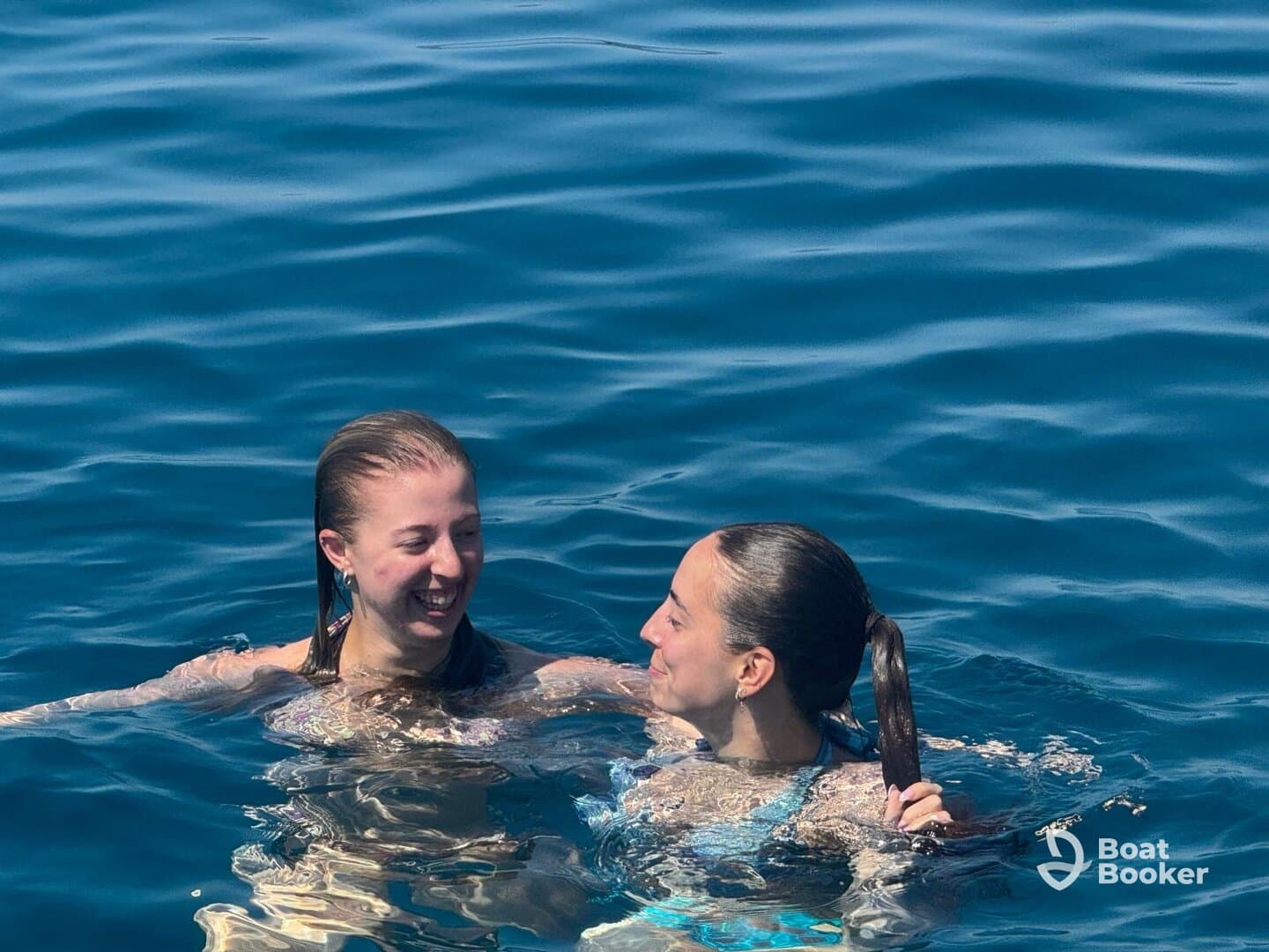Two friends enjoy a refreshing swim in crystal-clear waters, capturing the essence of summer fun and relaxation on the water.