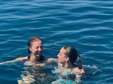Two friends enjoy a refreshing swim in crystal-clear waters, capturing the essence of summer fun and relaxation on the water.