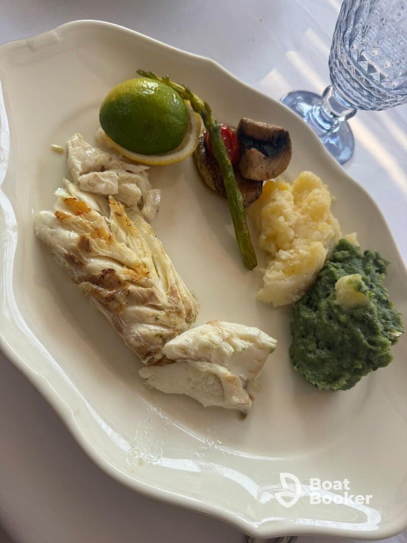 A beautifully plated dish featuring grilled fish, asparagus, and mashed potatoes, perfect for gourmet dining experiences on a boat.