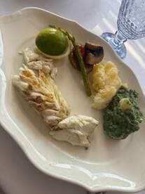 A beautifully plated dish featuring grilled fish, asparagus, and mashed potatoes, perfect for gourmet dining experiences on a boat.