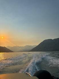 A stunning sunset view from a boat, showcasing the tranquil waters and mountainous backdrop — perfect for serene evening cruises.