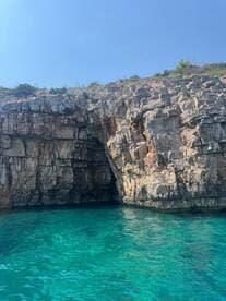 A stunning view of a rocky coastline with a cave entrance, surrounded by crystal-clear turquoise waters — a perfect destination for boat tours and exploration.