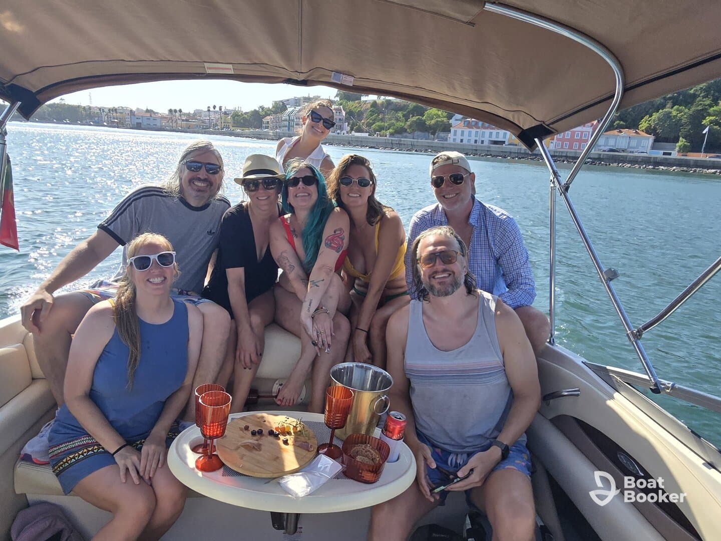 A lively group of friends enjoys a fun day on the water, celebrating with drinks and laughter aboard a pontoon boat.