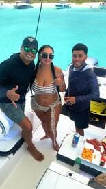 A lively group enjoys a fun day on the boat, showcasing snacks and drinks while celebrating together in the beautiful turquoise waters.