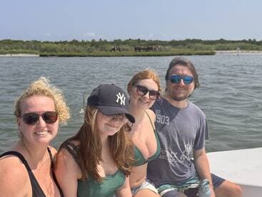 A cheerful group enjoys a day on the water, with wild horses grazing in the background — a perfect family adventure.