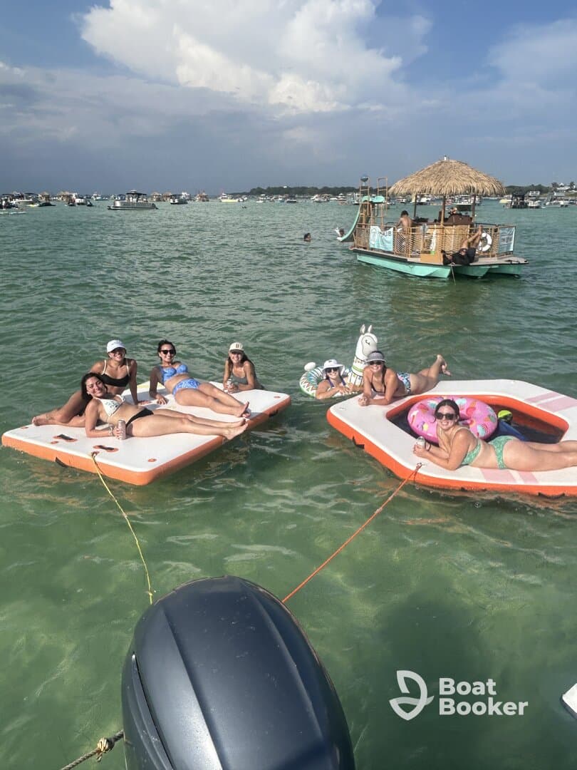 A lively group of friends enjoys a fun day on floating mats in the water, perfect for summer parties and relaxation.