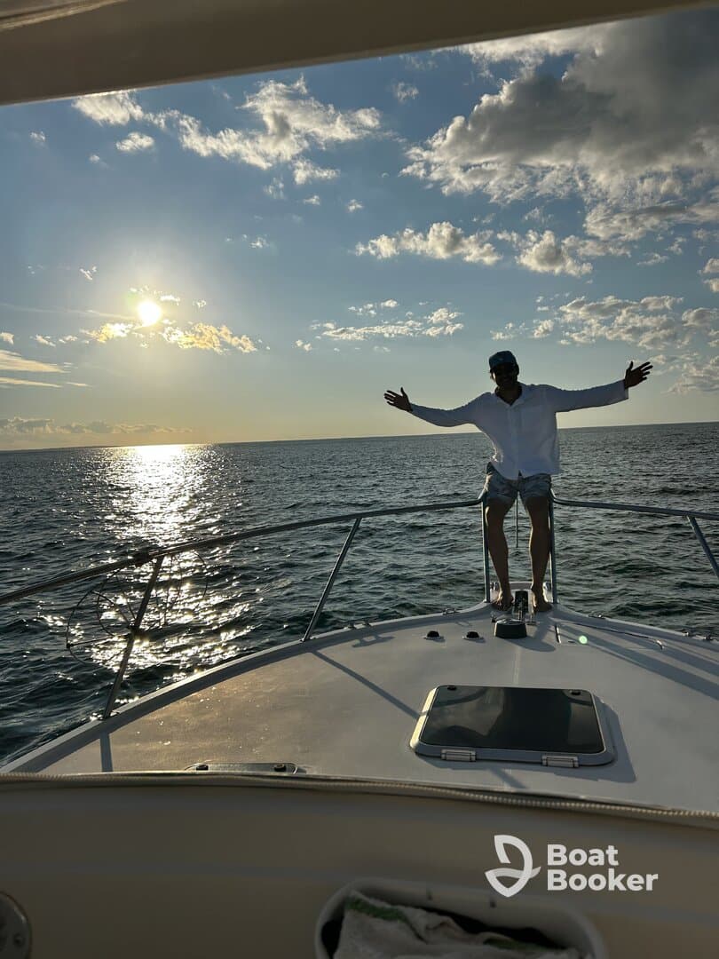 A man enjoys a stunning sunset aboard a boat, arms outstretched in celebration — a perfect moment for unforgettable memories on the water.