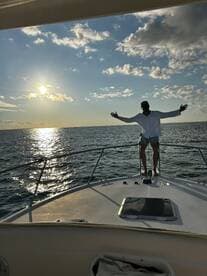 A man enjoys a stunning sunset aboard a boat, arms outstretched in celebration — a perfect moment for unforgettable memories on the water.