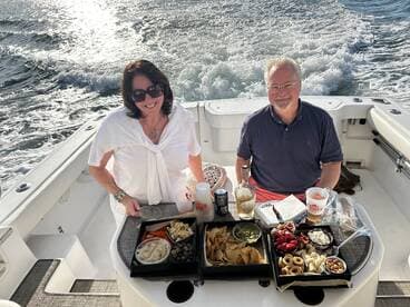 A couple enjoys a delightful spread of snacks and drinks aboard a boat, perfect for a relaxing day on the water.
