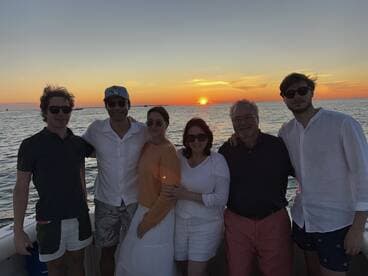 A cheerful group poses for a photo on a boat at sunset, capturing a memorable moment during their maritime adventure.
