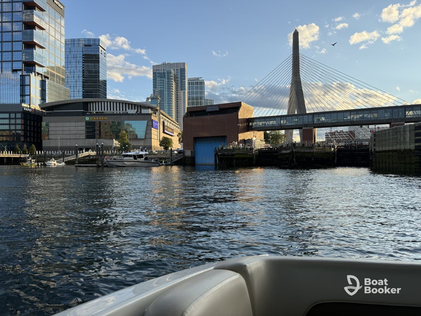 A scenic view of the Boston waterfront featuring the iconic TD Garden and a cable-stayed bridge, perfect for capturing the vibrant city atmosphere from the water.