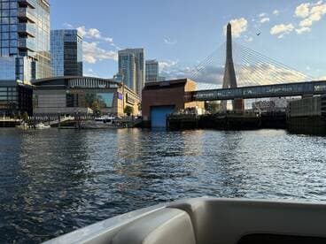 A scenic view of the Boston waterfront featuring the iconic TD Garden and a cable-stayed bridge, perfect for capturing the vibrant city atmosphere from the water.
