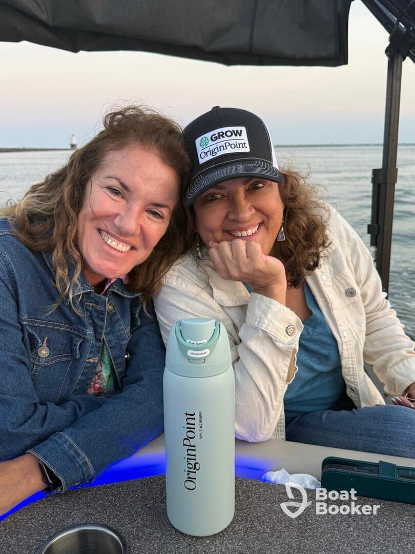 Two friends share a joyful moment on a boat, showcasing their camaraderie against a scenic waterfront backdrop — perfect for memorable outings and celebrations.