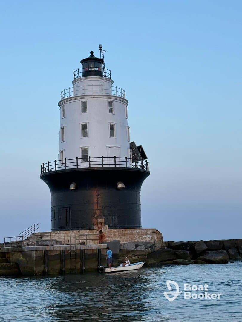 A small boat approaches a historic lighthouse, with people onboard enjoying the scenic view — a perfect moment for maritime exploration.