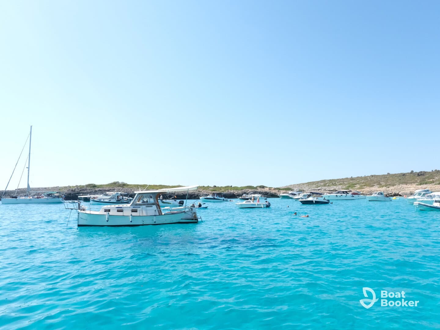 A vibrant scene of boats anchored in crystal-clear turquoise waters, with people enjoying the sun and swimming — a perfect summer getaway.