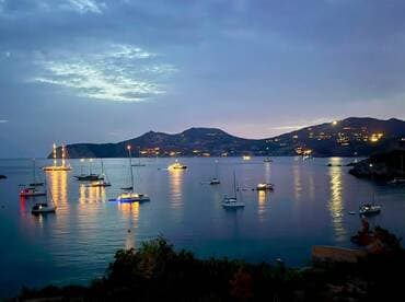 A picturesque harbor scene at dusk, featuring illuminated sailboats reflecting on calm waters — a serene moment perfect for evening boat tours or romantic getaways.