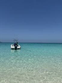 A speedboat anchored in crystal-clear waters, showcasing a serene day on the water — perfect for fishing or leisure activities.