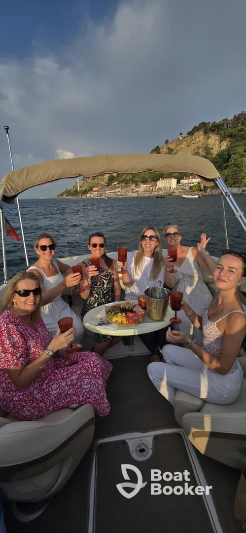 A joyful group of friends raises their cocktails aboard a boat, celebrating with delicious food and stunning views — perfect for a memorable outing on the water.