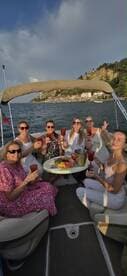 A joyful group of friends raises their cocktails aboard a boat, celebrating with delicious food and stunning views — perfect for a memorable outing on the water.