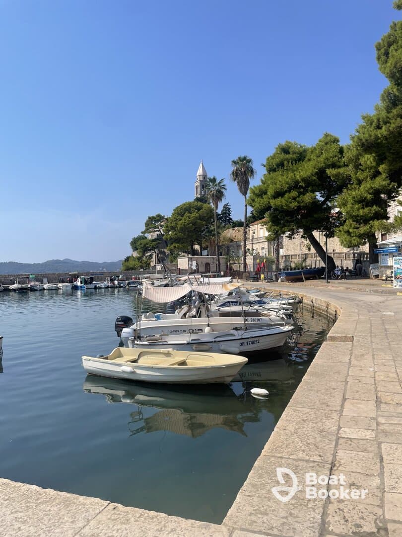 A serene view of small boats docked in a picturesque harbor, surrounded by lush greenery and historic architecture, perfect for a relaxing day by the water.