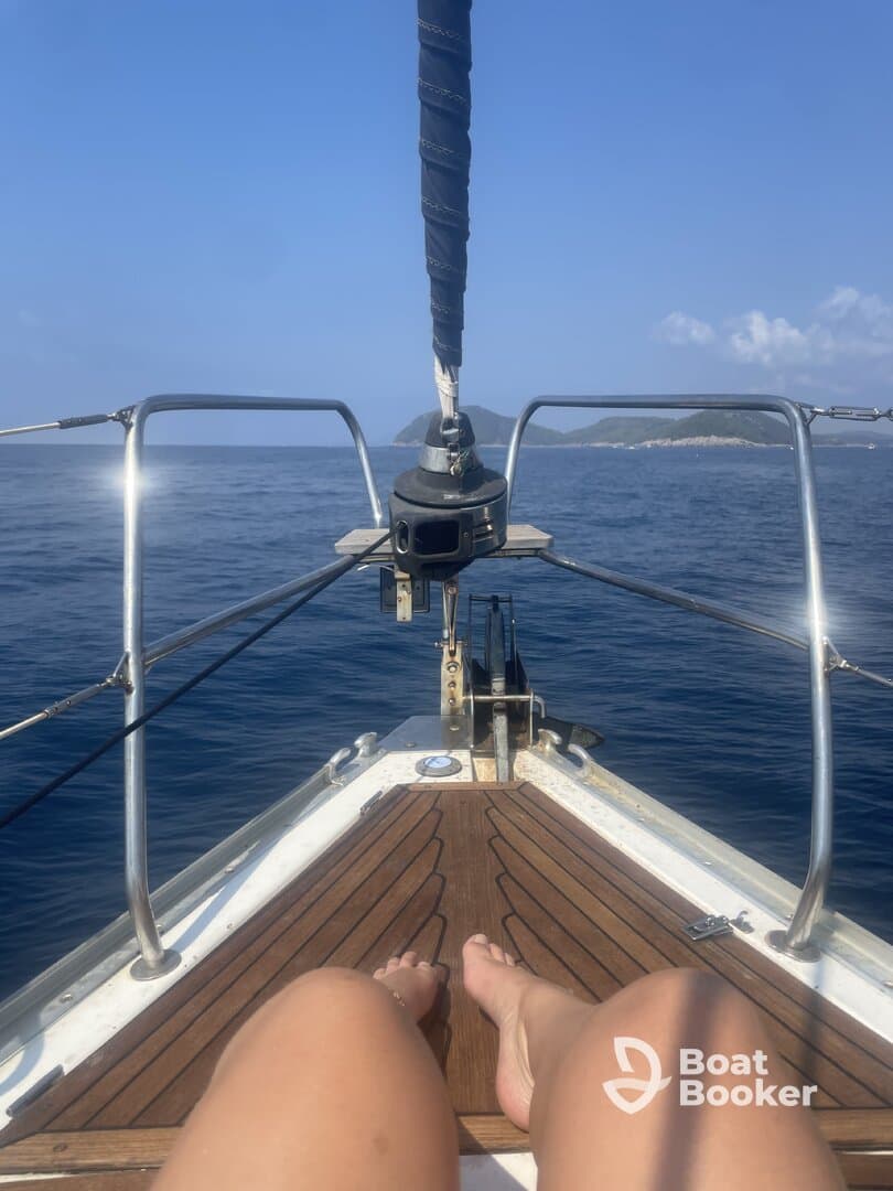 A relaxing moment on the bow of a sailboat, with feet dangling over the edge and a stunning ocean view — perfect for sailing enthusiasts seeking tranquility on the water.
