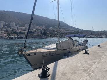 A beautiful yacht named Zara Bella docked at the marina, surrounded by scenic hills and charming coastal buildings, perfect for yacht charters.