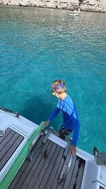 A child prepares to snorkel from the boat into the crystal-clear waters, showcasing a fun and adventurous day on the water.