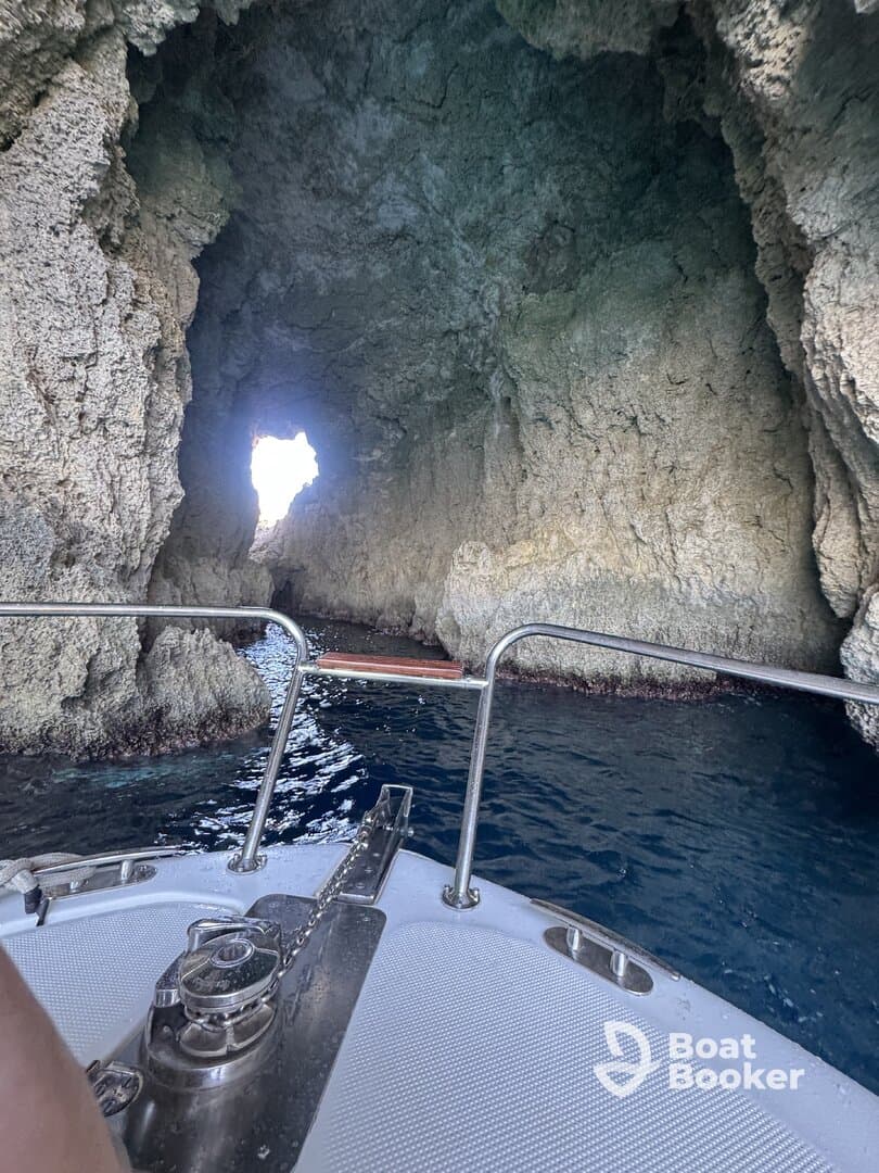 A stunning view from the bow of a boat as it navigates through a rocky cave, showcasing the beautiful coastal scenery — perfect for adventure seekers exploring hidden gems.