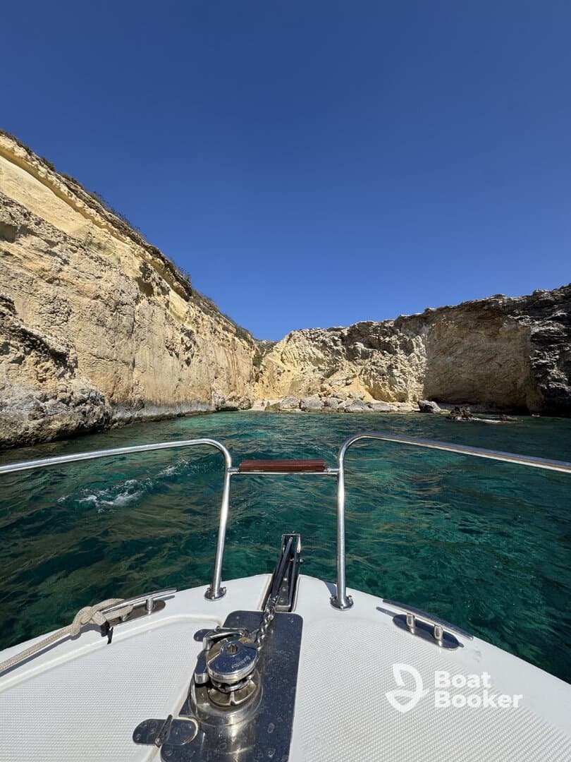 A stunning view from the bow of a boat navigating through crystal-clear waters surrounded by rocky cliffs, perfect for exploring coastal landscapes.