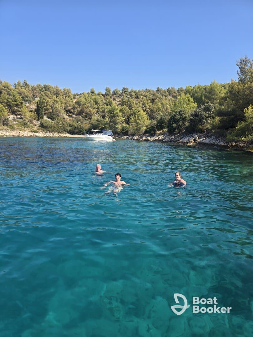 A group of friends enjoys a refreshing swim in crystal-clear waters, surrounded by lush greenery — a perfect summer getaway.