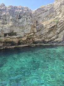 A stunning view of rocky cliffs rising above crystal-clear waters, showcasing the natural beauty of the coastline — perfect for eco tours and scenic boat trips.