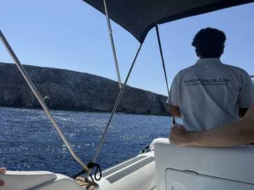 A scenic view from a boat with a passenger enjoying the ride, showcasing the stunning cliffs and sparkling ocean waters — perfect for exploring the coastline.