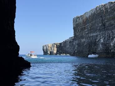 A scenic view of boats navigating through a stunning coastal landscape, showcasing the beauty of the cliffs and clear waters — perfect for adventure seekers exploring hidden gems.