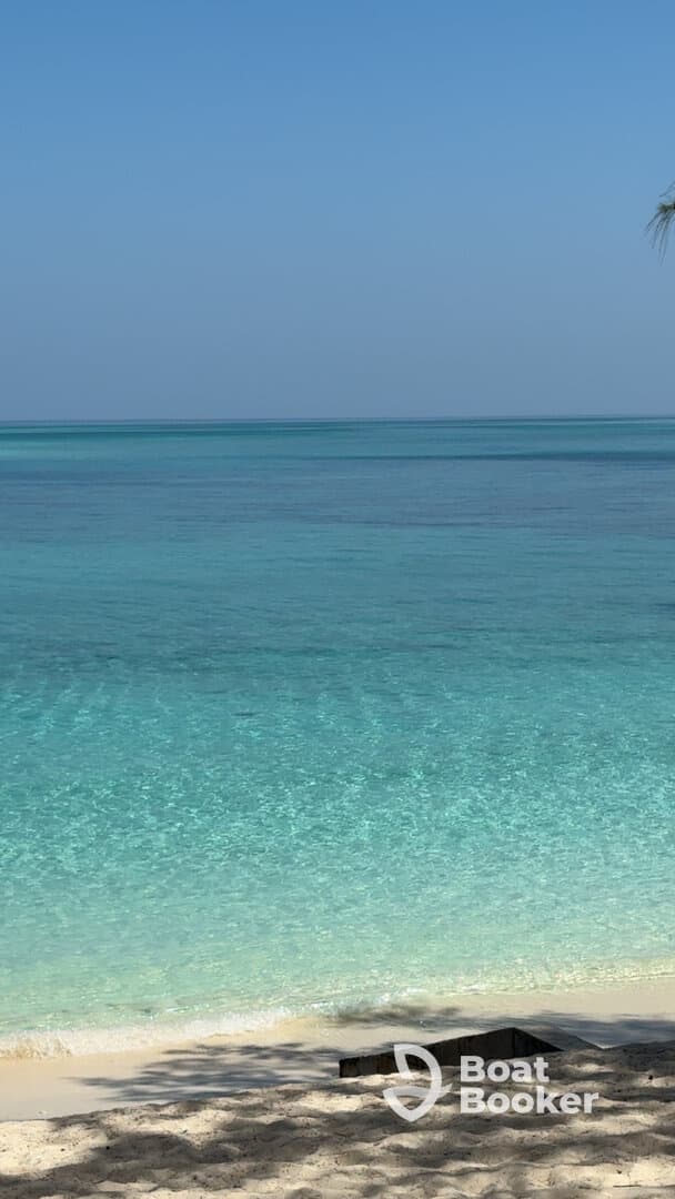 A serene view of clear turquoise waters meeting a sandy beach, perfect for relaxation and beach activities.