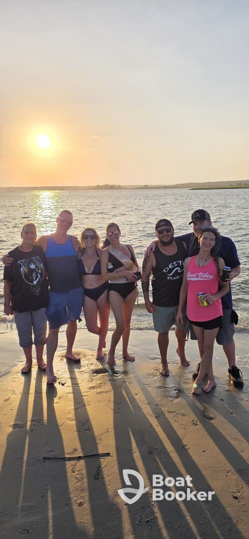A cheerful group poses together on the beach at sunset, capturing a memorable moment of celebration and camaraderie by the water.