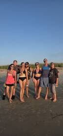 A lively group of friends enjoys a beach day, celebrating together with drinks and smiles — perfect for memorable summer outings.