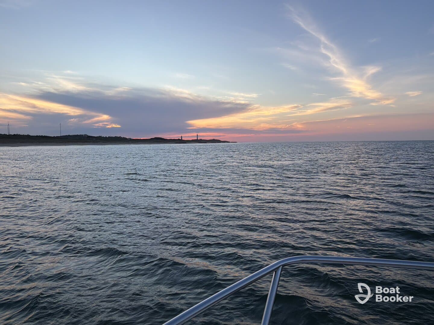 A serene sunset view over calm waters, showcasing the boat's bow in the foreground — perfect for tranquil evening cruises.
