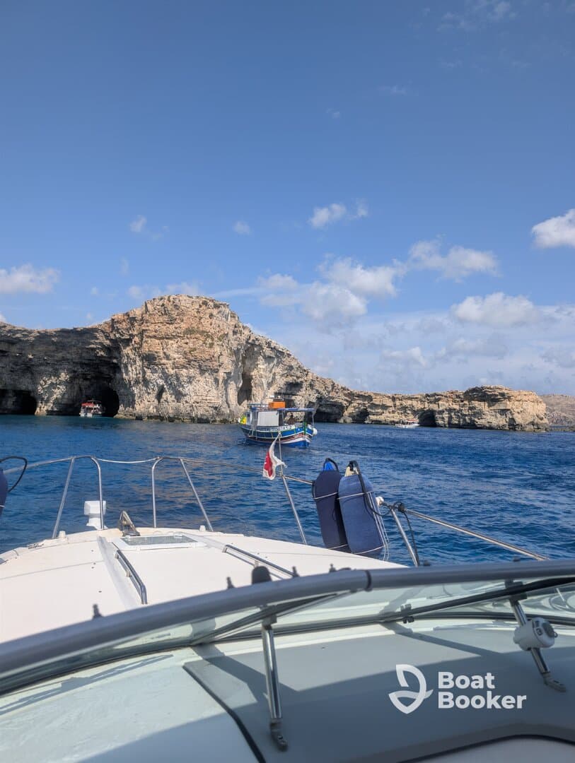 A scenic view from the bow of a boat navigating near stunning coastal cliffs, showcasing the beauty of the surrounding waters and rock formations.