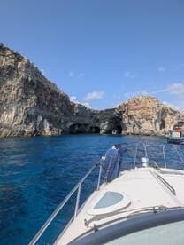 A stunning view of a boat navigating through coastal caves, showcasing the beautiful turquoise waters and rocky cliffs — perfect for adventure seekers exploring hidden gems.