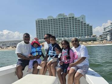 A joyful family enjoys a day on the boat, with children in life jackets and a beautiful beach backdrop — perfect for memorable family vacations.