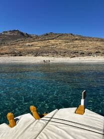 A group of people enjoys a sunny day at the beach, with crystal-clear waters and a picturesque backdrop, perfect for a fun day out on the boat.
