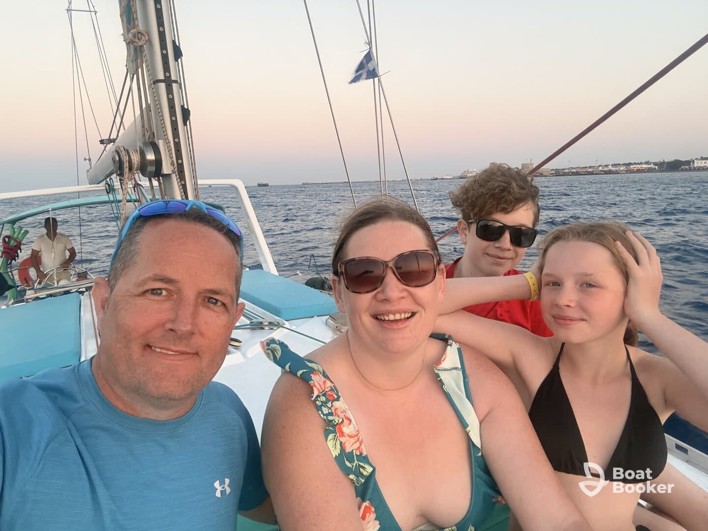 A joyful family captures a moment aboard a sailboat during sunset, creating lasting memories on the water.